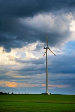 Dramatic sky over wind turbine on green field by Simon Dux