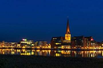 Uitzicht over de Warnow naar de Hanzestad Rostock in de avond van Rico Ködder