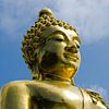 Gouden boeddha tekent af tegen blauwe lucht van Maurice Verschuur