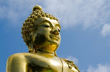Gouden boeddha tekent af tegen blauwe lucht