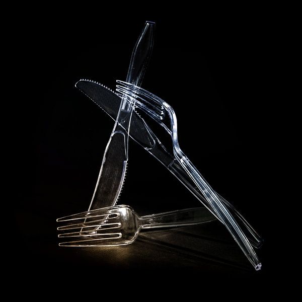 Transparent plastic cutlery, knives and forks against a black background, disposable tableware will  by Maren Winter