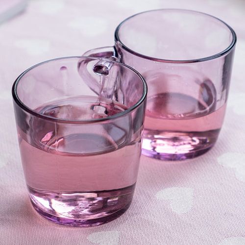 Ensemble de verres à thé roses avec liquide pour un fond particulièrement rose avec des coeurs blanc