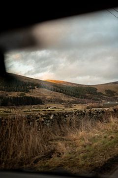 Uitzicht vanuit de auto over de Schotse heuvels waar de zon op komt. van Holly Klein Oonk