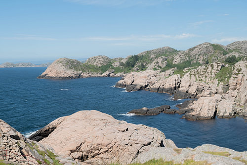 Rocky Norwegian coastline with pink granite and blue sea