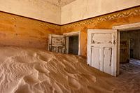 Kamer met duin in Kolmanskop, spookstad in de woestijn