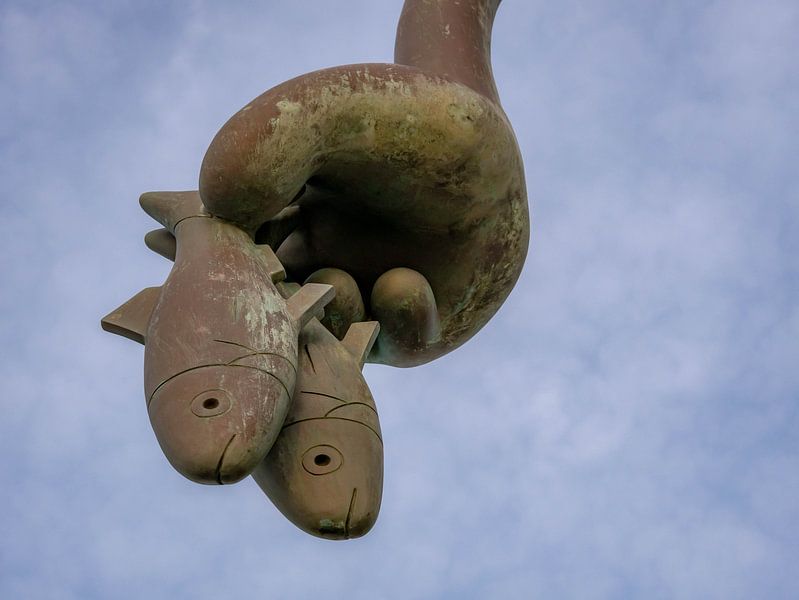 Een hand die vissen vasthoudt. Een kunstwerk van beelden aan zee scheveningen van Linda van der Meer