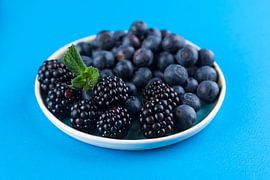 Blackberries on a blue plate against a blue background by Ans van Heck