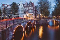 Verlichte bruggen over de Amsterdamse grachten in Amsterdam op een zomer avond van Michiel Dros thumbnail