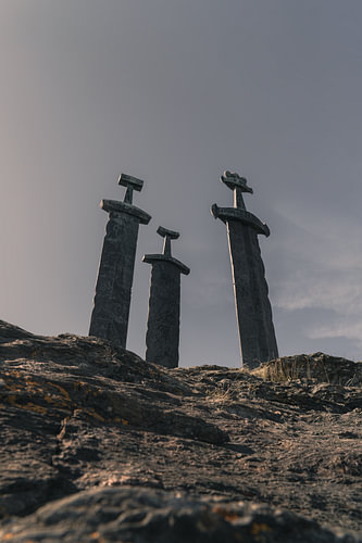 Wikinger-Geschichte – Vertikaler Fotodruck der drei „Sverd i fjell“-Schwerter bei Hafrsfjord bei Sonnenuntergang