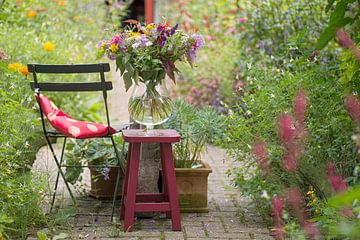 Doorkijkje in zomerse tuin met vaas met bloemen