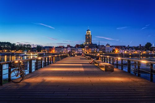 Iemand kijkt naar Deventer tijdens het blauwe uur aan de IJssel.