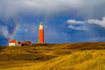Texel lighthouse in the dunes with a rainbow during a stormy aut
