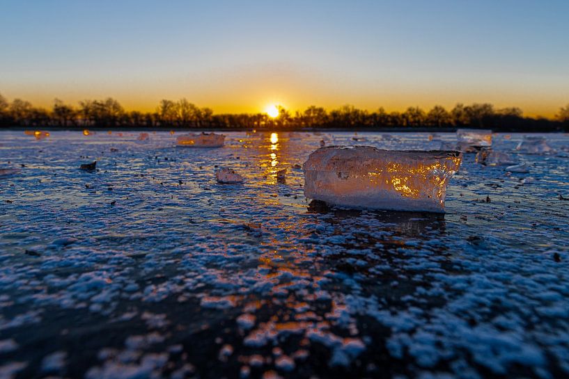 Chunk of ice on a frozen lake during a warm sunrise by Kim Willems