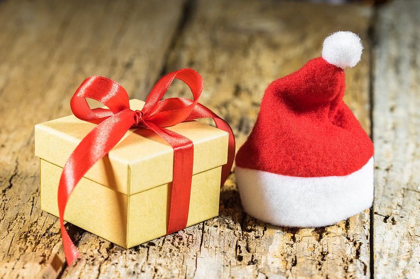 Christmas present with ribbon bow and red santa cap by Alex Winter