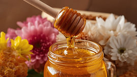 Honey in a jar with a wooden honey spoon by Bo Valentino