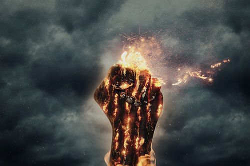 verkoolde vuist in vlammen stijgt op voor donkere wolken