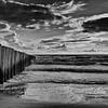 poteaux de plage sur la côte de la mer dans les brise-lames en noir et blanc sur Groothuizen Foto Art
