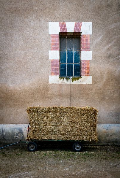 Rustic Farm Scene With Hay Bale Wagon Beside A Beige Wall And Old Window Facade by ChrisWillemsen