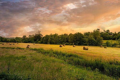 Landschap met hooibalen tijdens zonsondergang