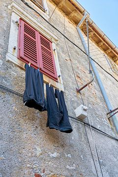 Clothesline with pants on a facade in the old town of Krk by Heiko Kueverling