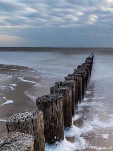 poteaux dans la mer sur Ameland pendant l'heure bleue
