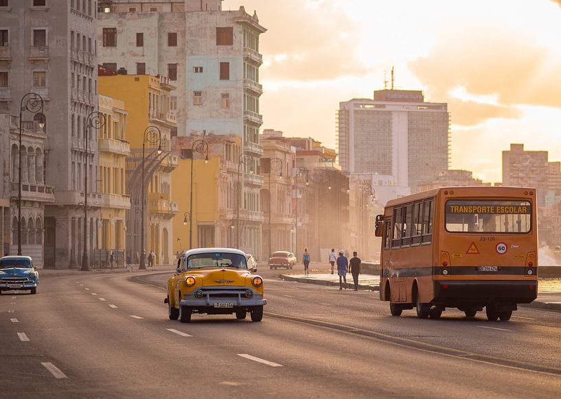 Klassieke auto's en schoolbus bij zonsondergang in Havana, Cuba van Teun Janssen