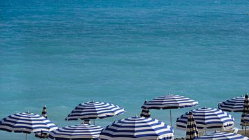 Blauwe en witte parasols op het strand in Nice, Frankrijk van Lensw0rld