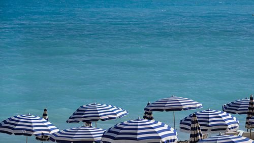 Blauwe en witte parasols op het strand in Nice, Frankrijk