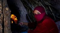 Woman baking bread in an open fire oven by Rene Siebring thumbnail