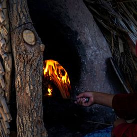 Woman baking bread in an open fire oven