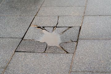 dalle de trottoir détruite avec une flaque d'eau sur Heiko Kueverling