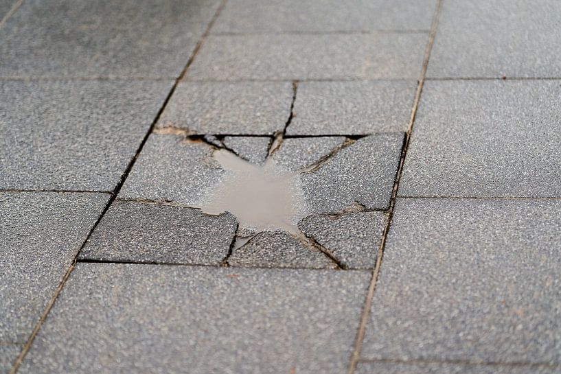 Destroyed pavement slab with a puddle by Heiko Kueverling