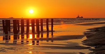 Zonsondergang achter strandpalen van Marco Weening