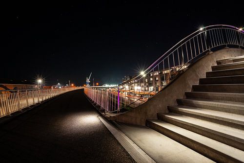Illuminated footpath with stairs and railings and view over Harlingen harbor