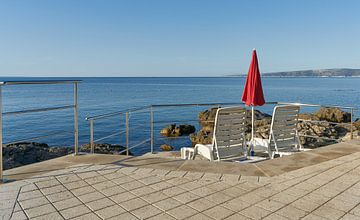 Parasol en ligstoelen aan de Adriatische kust bij de stad Krk