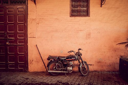 Vintage brommer tegen rode muur in Marrakesh