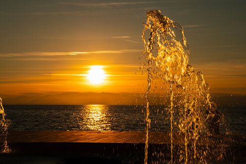 Gouden zonsondergang met fontein aan zee