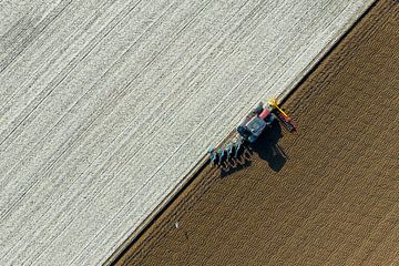 Tractor ploegt de grond voor het planten van gewassen van bovenaf gezien