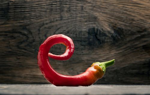 Prachtig gebogen rode chilipeper op een houten tafel