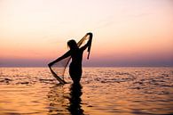 Naakte vrouw met een visnet bij ondergaande zon in de waddenzee van Arjan Groot thumbnail
