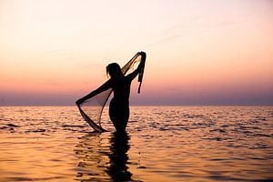 Naakte vrouw met een visnet bij ondergaande zon in de waddenzee van Arjan Groot