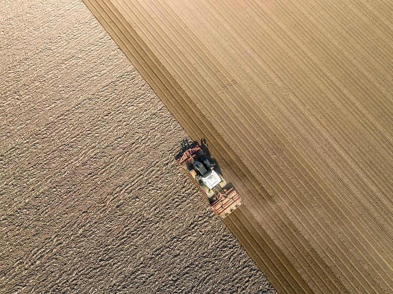Tractor maakt de grond klaar voor het planten van gewassen van bovenaf gezien van Sjoerd van der Wal Fotografie