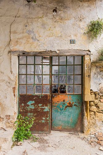 Vieux mur avec des portes métalliques rouillées, de couleur turquoise et orange, d'un atelier