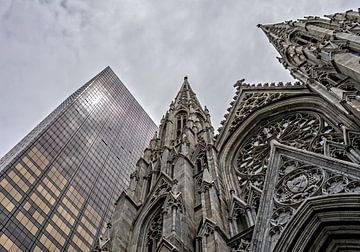 Omhoogkijken naar de St. Patrick's kathedraal in New York naast wolkenkrabber. van John Duurkoop