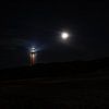 Met de maan naast de vuurtoren vanaf het strand. van Anneke Hooijer