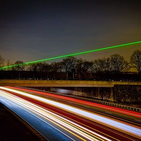 Lumière laser au-dessus de l'autoroute. Photo à longue exposition sur Twan van den Hombergh