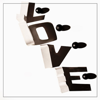 LOVE- met schaduw van witte letters en zwarte balletjes.