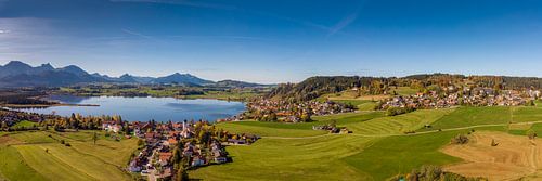 Luftbildpanorama vom Hopfensee mit Alpen und blauem Himmel im Hintergrund