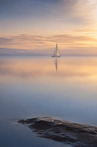Golden Silence – A sailing boat on calm waters at sunset