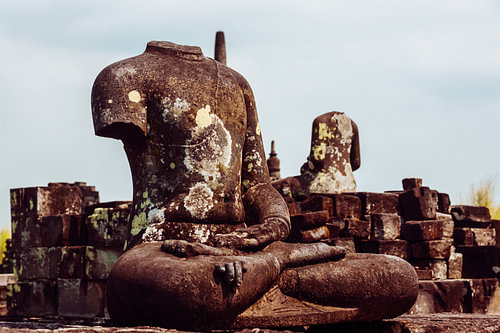 Enthaupteter Buddha zwischen Trümmern
